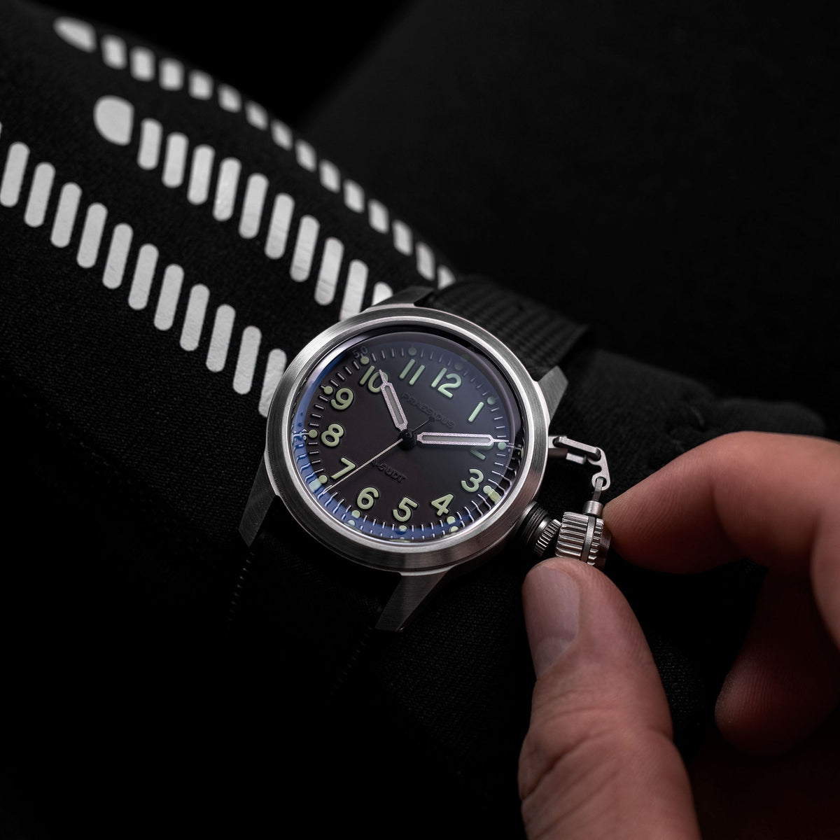 A-5 UDT black military field watch on black rubber Tropic strap on wrist being adjusted by hand