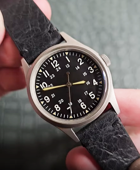 Jungle Field black dial watch held in hand
