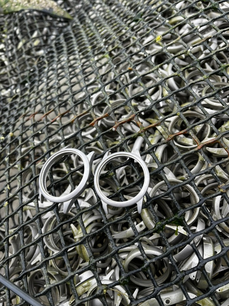 Two Neptune 44 watch cases resting on a marine-weathered basket containing more cases