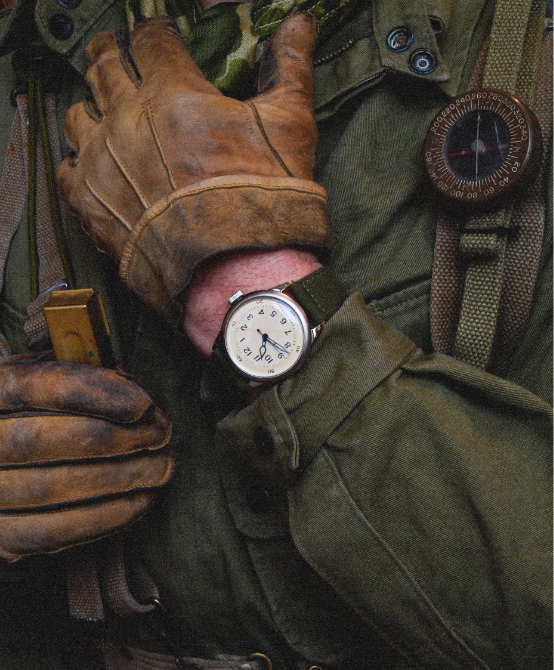 Gloved hand wearing an A-11 Tom Rice watch with WWII gear