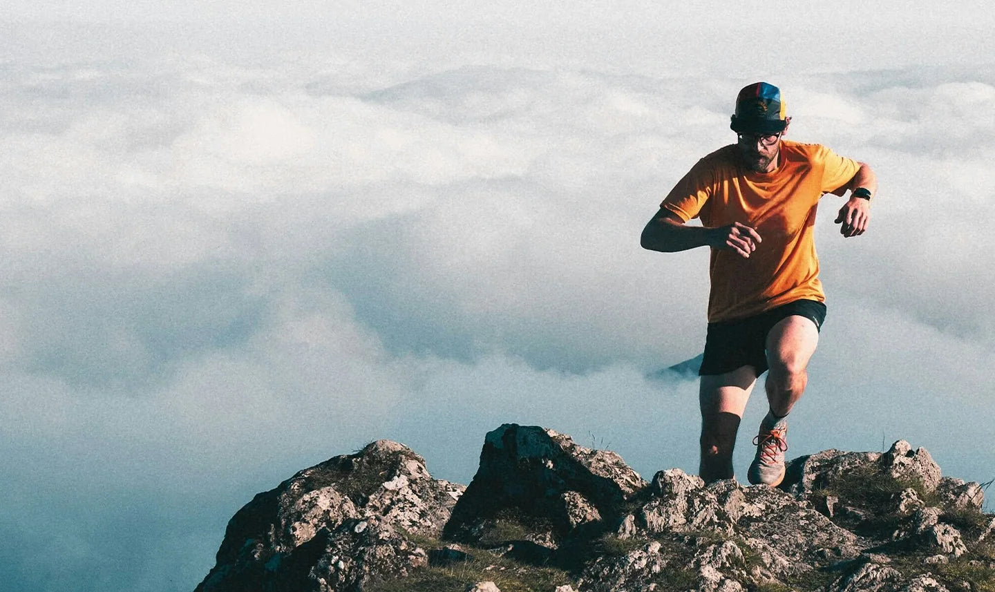 A runner crossing a rocky mountain ridge above the clouds