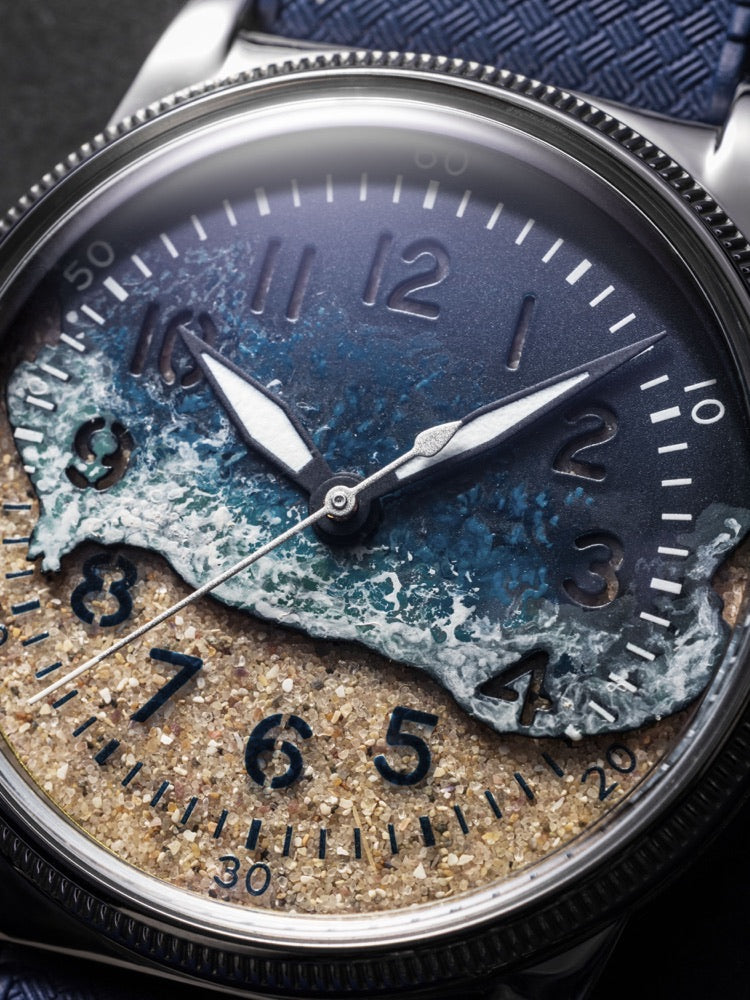 Surf Blue dial detail showing individually hand-painted waves above real Utah Beach sand